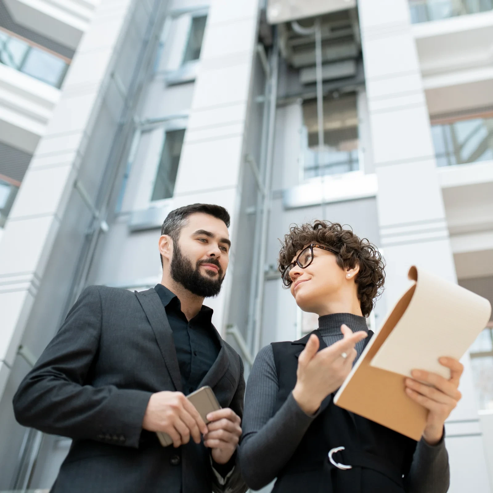 Two colleagues reviewing documents outdoors.