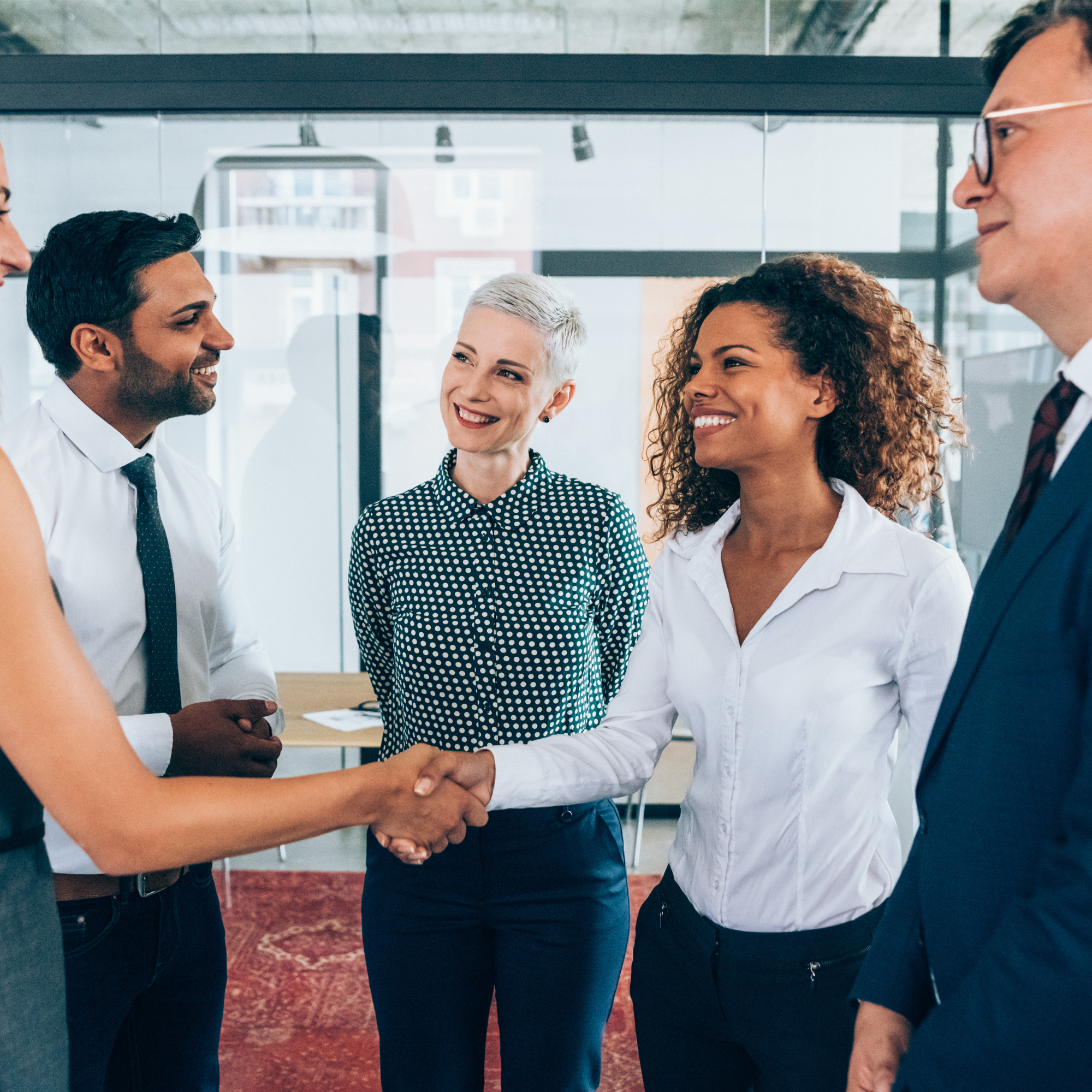 Professionals greeting one another during a group meeting.