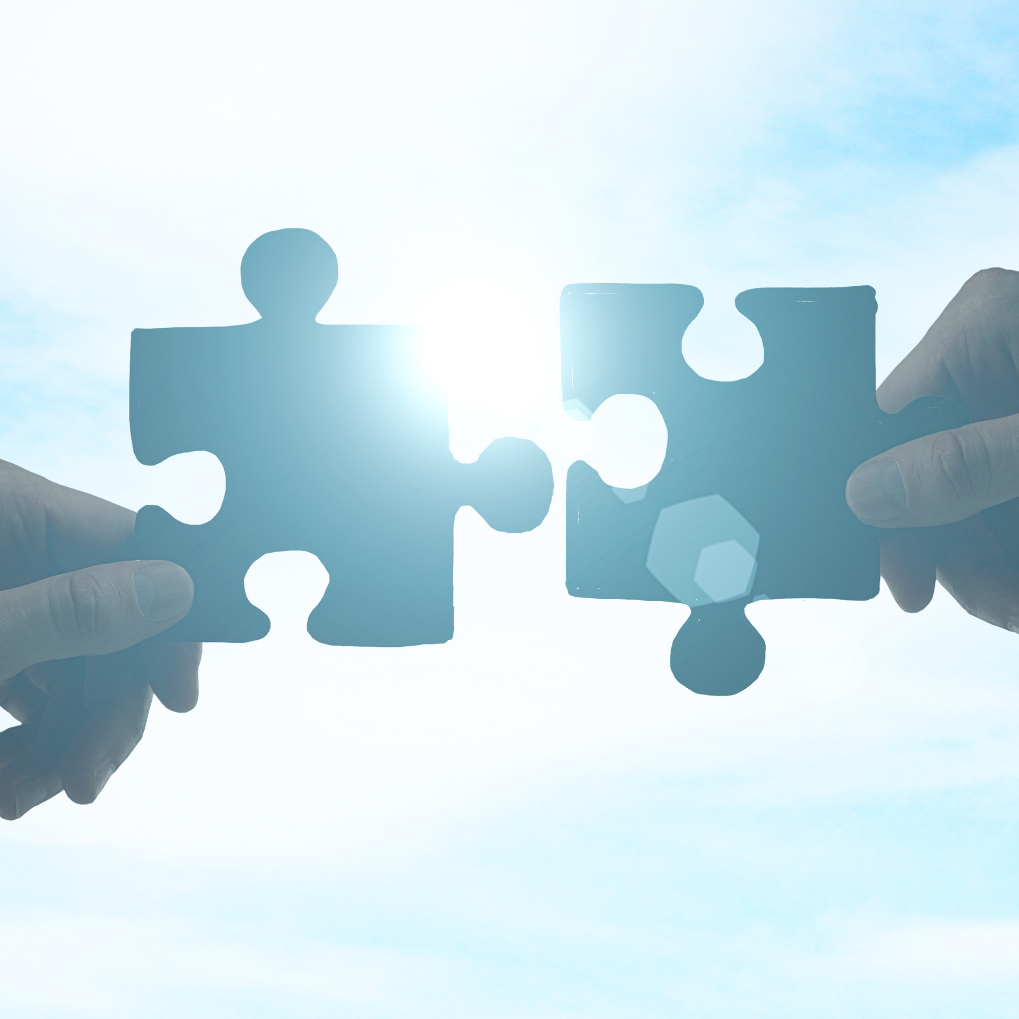 Two hands bringing complementary puzzle pieces together.